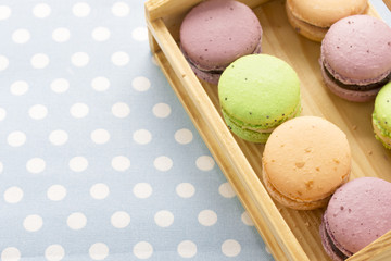 Set of various colored macaroons on wooden plate