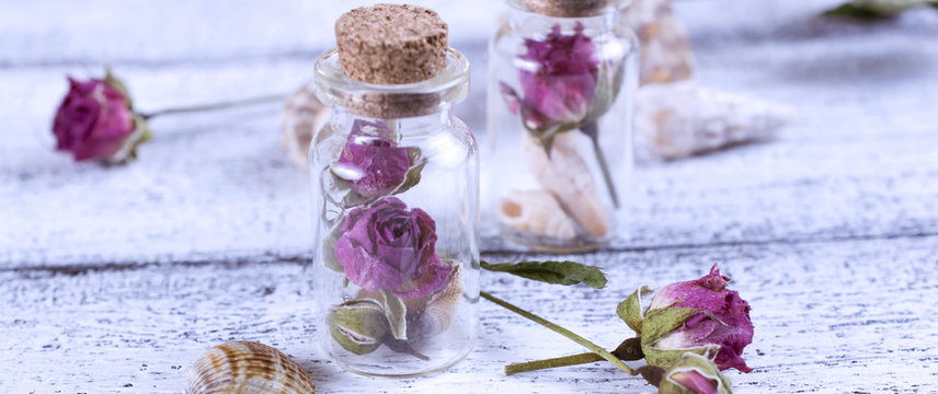Small glass bottle filled dry roses and seashells