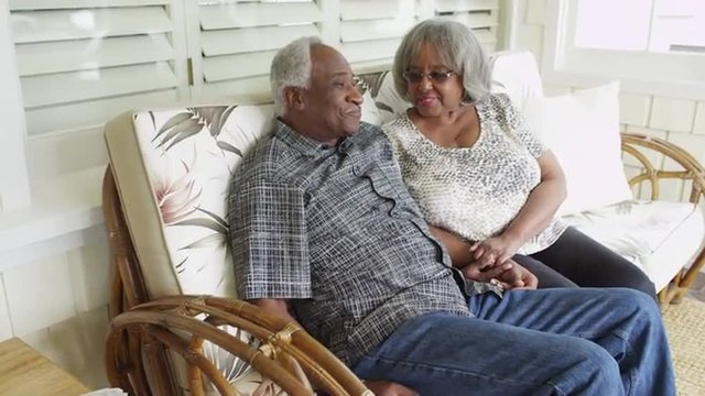 Mature african couple sitting on couch talking and smiling