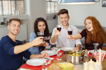 freunde prosten mit einem glas rotwein in die kamera
