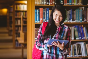 Smiling student in library using tablet