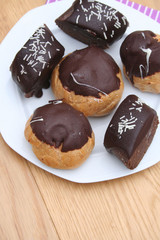 bignè e dolci al cioccolato su piatto su tavolo di legno