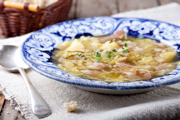 Cabbage soup with bacon, potato, meat, ceramic plate, bread 