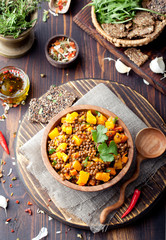 Lentil with carrot and pumpkin ragout in a wooden bowl.