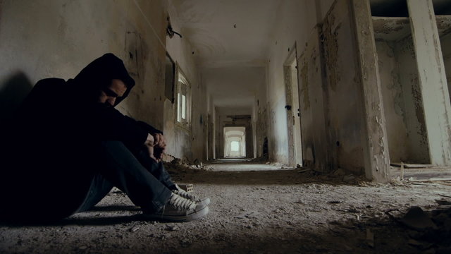 Troubled young man in wrecked abandoned building 