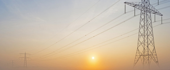 Fototapeta premium Power line in a foggy field at sunrise
