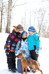 Fototapeta na wymiar Mother with children and a dog walking in the winter on walk