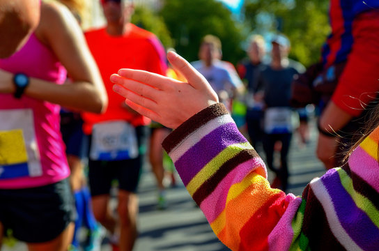Marathon running race, support runners on road, child's hand giving highfive, sport concept
