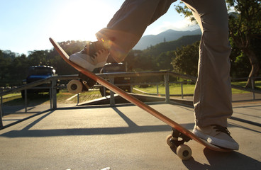 Fototapeta na wymiar skateboarder legs at sunrise skatepark