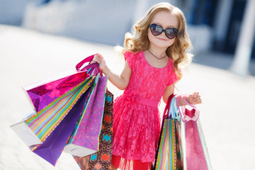 Little girl with shopping bags goes to the store