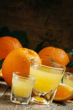 Fresh orange juice in a large and a small glass on the old woode