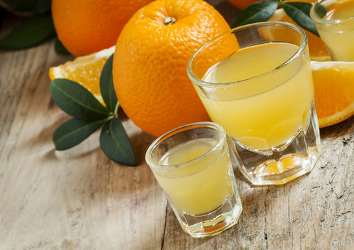 Fresh orange juice in a large and a small glass on the old woode