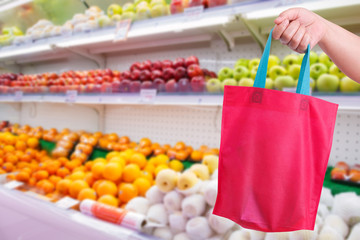 closeup hand holding reusable bag in supermarket