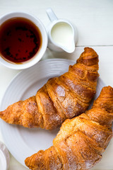 Two Fresh Croissants with Icing, Tea and Milk are ready for the