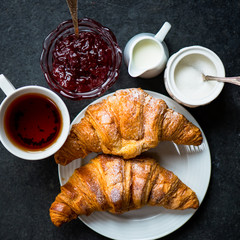 Croissants with Icing, Cup of Tea, Milk, Sugar and Strawberry Ja