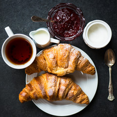 Croissants with Icing, Cup of Tea, Milk, Sugar and Strawberry Ja