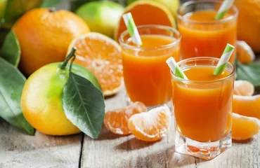 Crédence de cuisine en verre imprimé Jus Fresh juice of ripe mandarins in a small glass with striped stra
