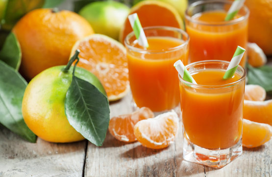 Fresh Juice Of Ripe Mandarins In A Small Glass With Striped Stra