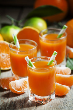 Fresh juice of ripe mandarins in a small glass with striped stra