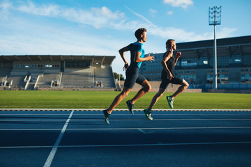 Young men running on race track - Powered by Adobe