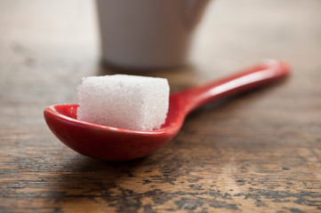 sucre en morceau et cuillère rouge en gros plan