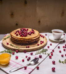 delicious pancakes with berries and a cup of tea, honey and spoon on wooden rustic background close up