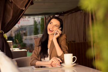 Cute young business woman in a cafe talking on the phone