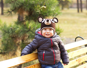 Happy baby in a funny hat on a walk. Walking outdoors in the fall. autumn leaves
