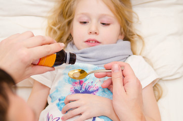 Doctor giving a spoon of syrup to little girl
