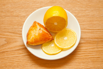 Lemon and bun on wooden background, top view
