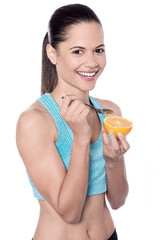 Fit young lady eating juicy orange