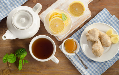 Teapot and cup of tea with lemon, ginger and mint
