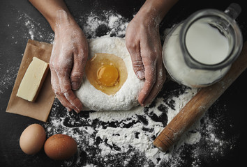 Professional female baker cooking dough with eggs, butter and milk for Christmas cookies.  - obrazy, fototapety, plakaty