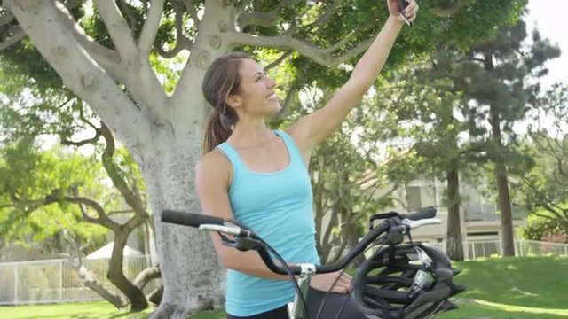 Young woman on a bike taking a selfie at park