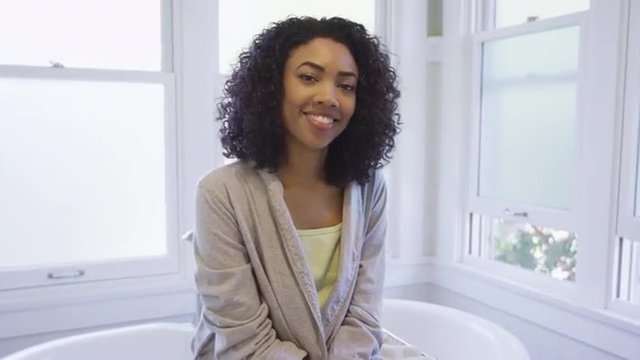 Beautiful black woman sitting in bathroom smiling