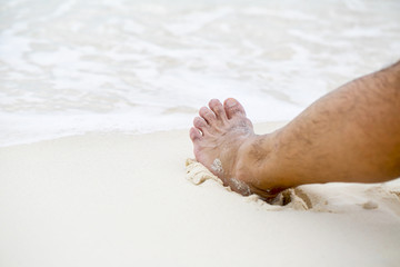 Man's bare foot on the Caribbean beach.