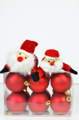 Christmas Decoration / close up of a plastic box  with red christmas tree balls and Santa Claus on white background, vertical
