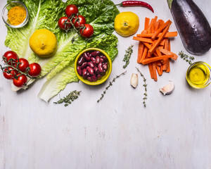 Ingredients for cooking vegetarian food,  squash, beans, tomatoes on a branch, lemon, lettuce, sliced carrots border, place for text on wooden rustic background top view vegetarian concept