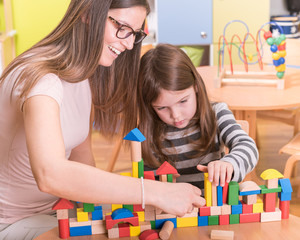Kindergarten Teacher and Kid Playing with Wooden Building Blocks