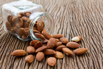 Almonds pour from glass bottle on wooden table