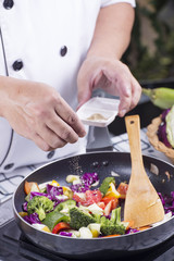 Chef putting Salt to the pan for cooking