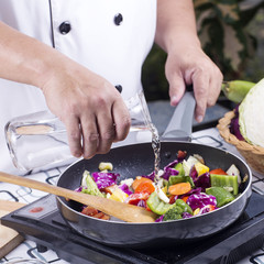 Chef pouring soup to the pan for cooking