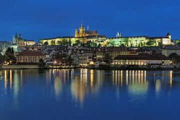 Fototapeta na wymiar Prague, Czech Republic. Evening view of the Prague Castle with St. Vitus Cathedral and Mala Strana district with St. Nicholas Church and Mala Strana Bridge Towers from the shore of Vltava river.
