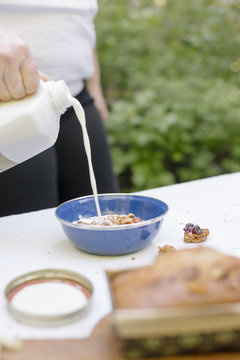 Woman Pouring Fresh Milk Into A Bowl Of Cereal.