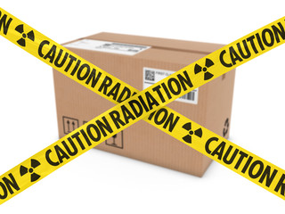Radioactive Attack Parcel Concept - Cardboard Box behind Caution Radiation Tape Cross