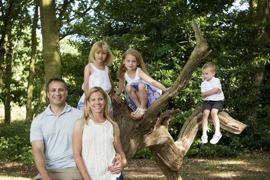 Family with three children by a tree in a forest, posing for a picture.