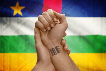 Barcode ID number on wrist of dark skinned person and national flag on background - Central African Republic