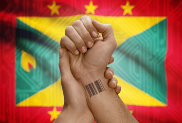 Barcode ID number on wrist of dark skinned person and national flag on background - Grenada