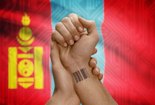 Barcode ID number on wrist of dark skinned person and national flag on background - Mongolia