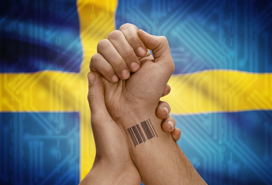 Barcode ID number on wrist of dark skinned person and national flag on background - Sweden